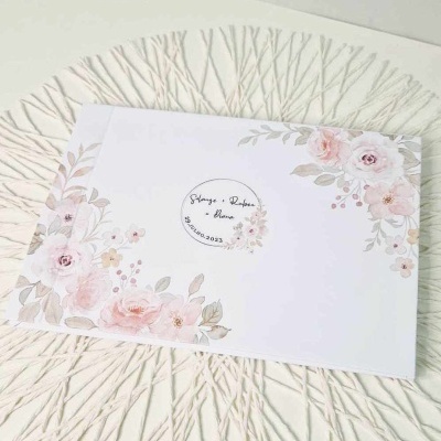 Envelope floral branco com texto centralizado sobre superfície texturada branca