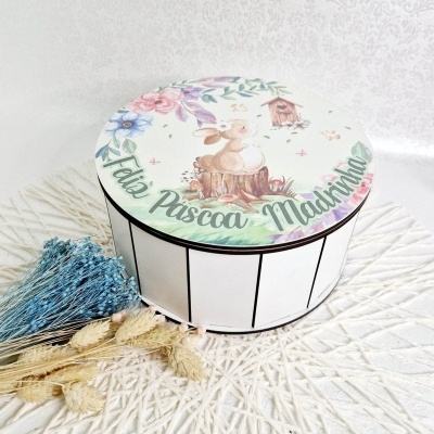 Caixa redonda com tampa decorada de coelho e flores, texto 'Feliz Páscoa, Madrinhas'