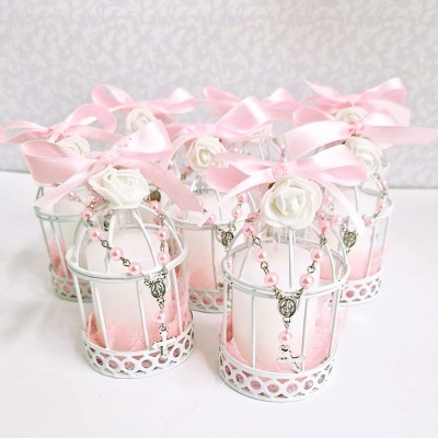 Velas decorativas brancas rosa em gaiolas de metal branco com fitas e terços cor-de-rosa