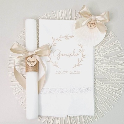 Conjunto para batizado com vela branca, toalha bordada branca, tag de madeira com fita bege e concha decorativa com fita laço.