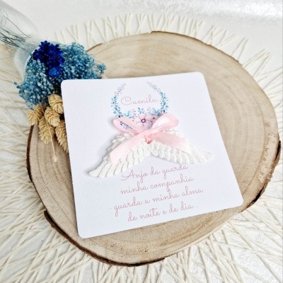 Cartão com texto e anjo decorativo sobre prato de madeira com flores secas azuis
