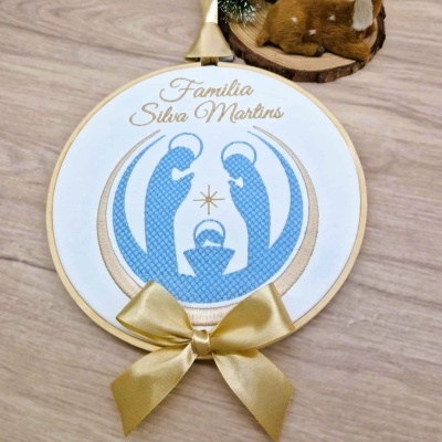 Quadro bordado da Sagrada Família em bastidor de madeira com laço dourado.