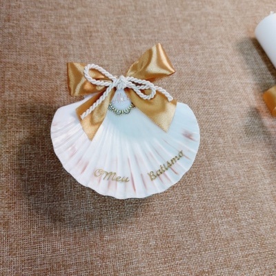 Concha branca decorada com laço dourado e cordão branco com pérolas