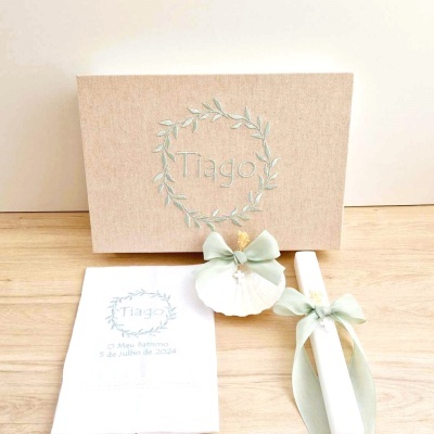 Convite para batizado com caixa kraft, vela com fita verde e concha e convite branco, com texto em português.
