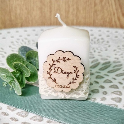 Vela branca quadrada com etiqueta de madeira personalizada com nome e data, decorada com renda, folha verde e fundo com padrão circular branco