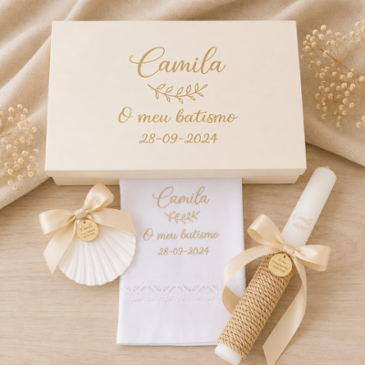 Conjunto de batismo com toalha branca bordada, vela decorada e concha, tudo embalado em caixa branca com texto dourado
