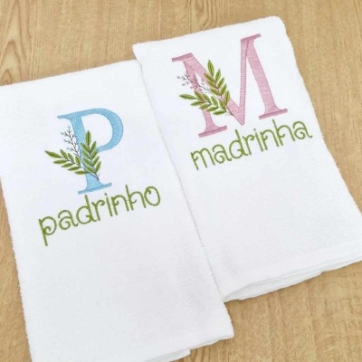 Dois panos de cozinha brancos bordados com as palavras padrinho e madrinha