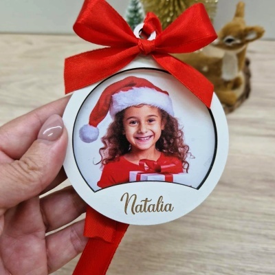 Etiqueta redonda branca com fotografia de criança com gorro de Natal e laço vermelho