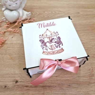 Caixa branca com ilustração de carrossel e fita rosa