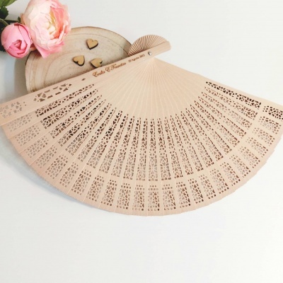 Leque decorativo em madeira com padrões recortados e texto gravado