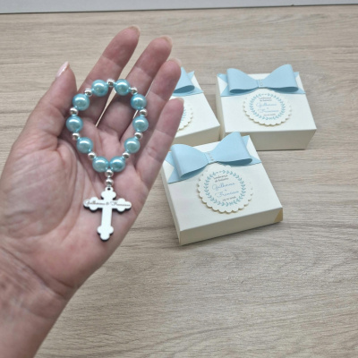 Pulseira azul com cruz prateada e caixas com laços azuis e etiquetas em madeira