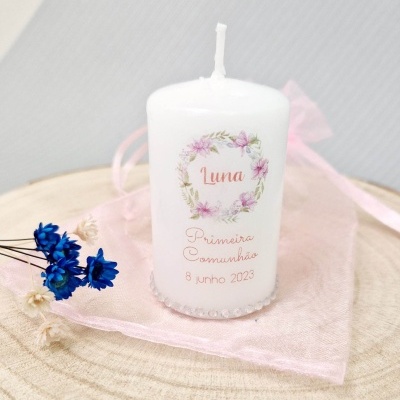 Vela branca decorativa com estampa floral e texto para Primeiro Comunhão sobre base de madeira e tecido rosa