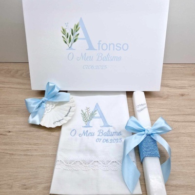 Conjunto de batismo com toalha, vela, concha e caixa brancas com decoração azul e texto gravado.