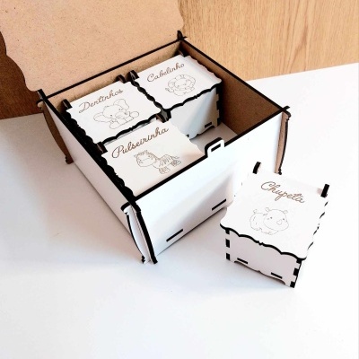 Conjunto de caixas de madeira brancas com desenhos a preto e palavras em português numa caixa maior castanha