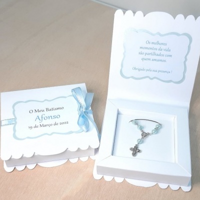Caixas de batismo brancas com pulseira azul e crucifixo, decoradas com fita azul clara