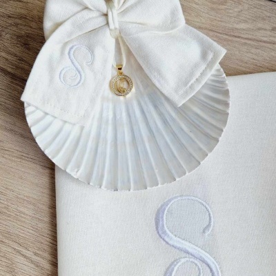 Conjunto branco com laço, concha, pendente dourado e toalha bordada com letra S