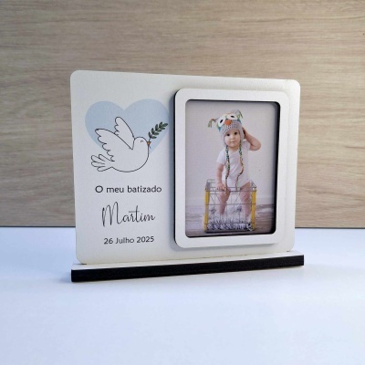 Porta-retrato branco com foto de criança, desenho de pomba e texto sobre batizado
