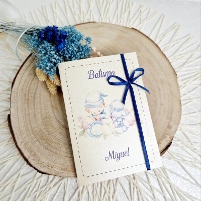 Convite de batismo com ilustração de bebê e fita azul sobre madeira redonda