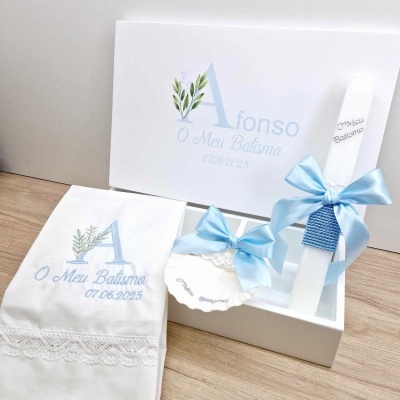 Conjunto de batismo com vela decorada, toalha bordada e medalha em caixa branca.