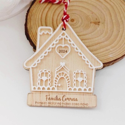 Enfeite natalício em madeira em forma de casa com decoração branca e texto gravado.