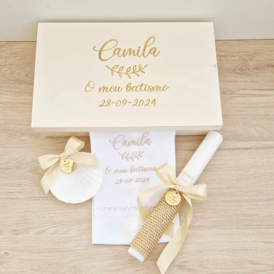 Conjunto de batismo com caixa branca, toalha bordada, concha decorativa e vela com laço.