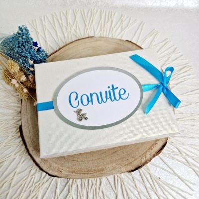 Caixa de convite branca com laço azul e etiqueta com palavra 'Convite' em azul