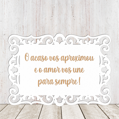 Placa decorativa branca com texto em português dourado sobre fundo de madeira clara