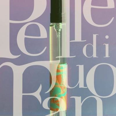 Clear spray bottle with black nozzle and colorful label on a pink surface