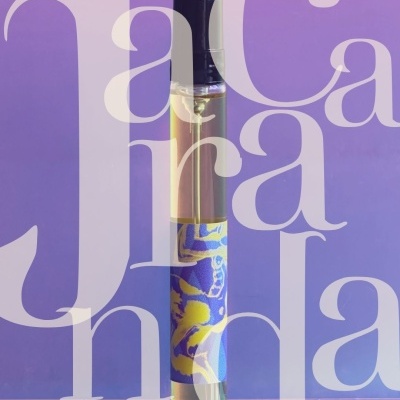 Glass bottle with black cap and blue-yellow label on purple background