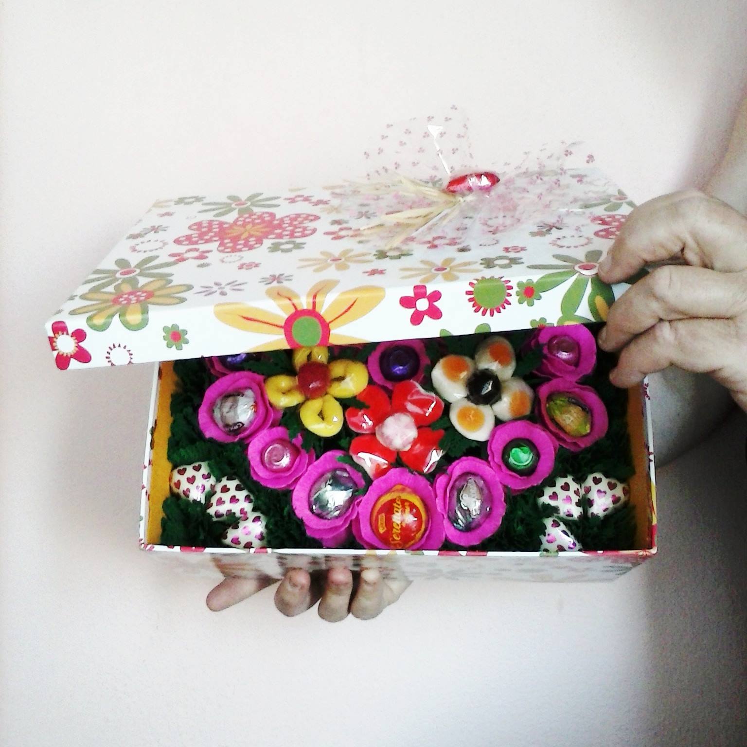 Caixa decorativa floral parcialmente aberta com peças coloridas no interior