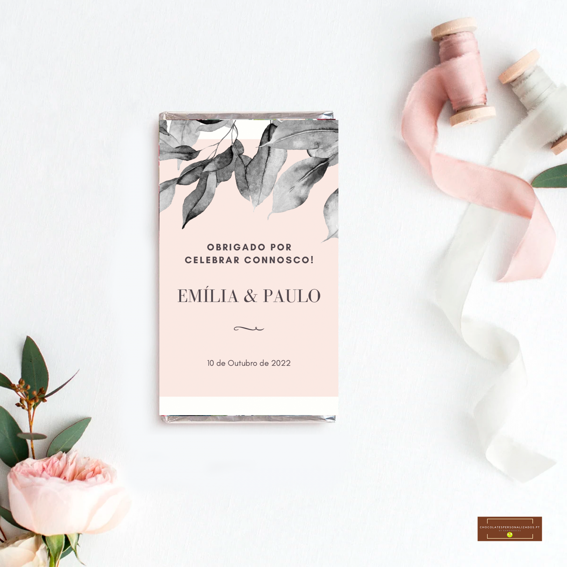 Barra de chocolate embrulhada com design floral cinza e rosa, fitas de tecido e flor rosa