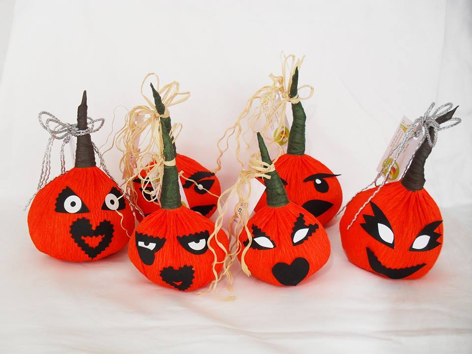 Seis abóboras decorativas de papel alaranjadas com expressões faciais e cordões para pendurar