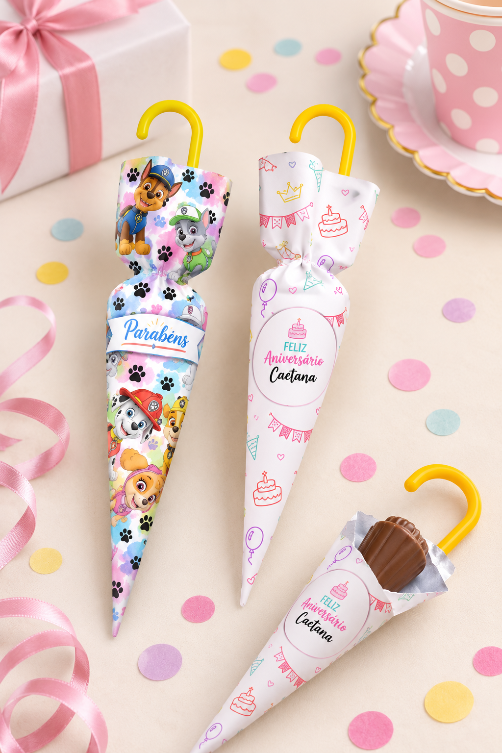 Três chocolates em forma de guarda-chuva embalados para festa infantil com desenhos de cães e motivos de aniversário.