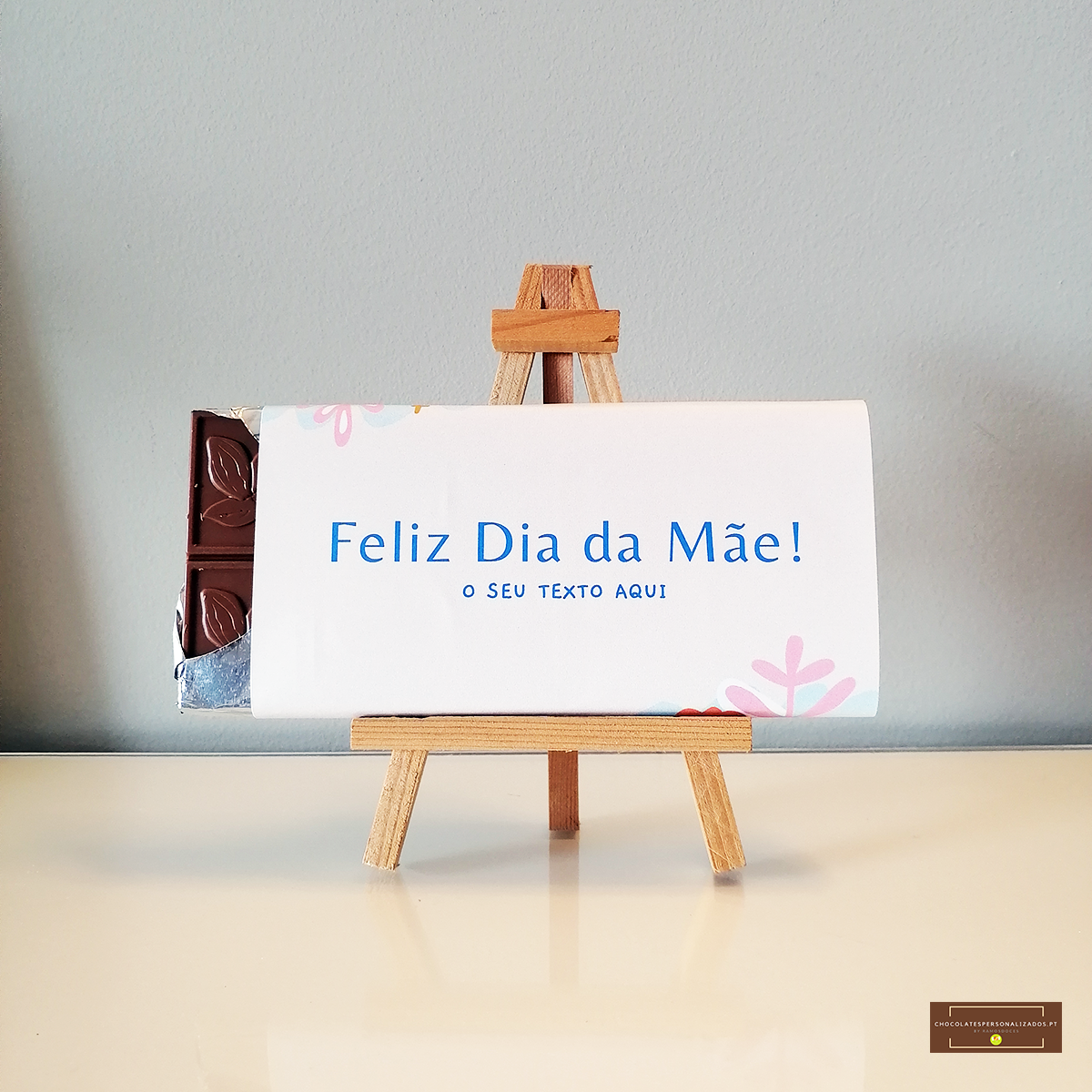 Barra de chocolate embrulhada com texto 'Feliz Dia da Mãe!' em cavalete de madeira