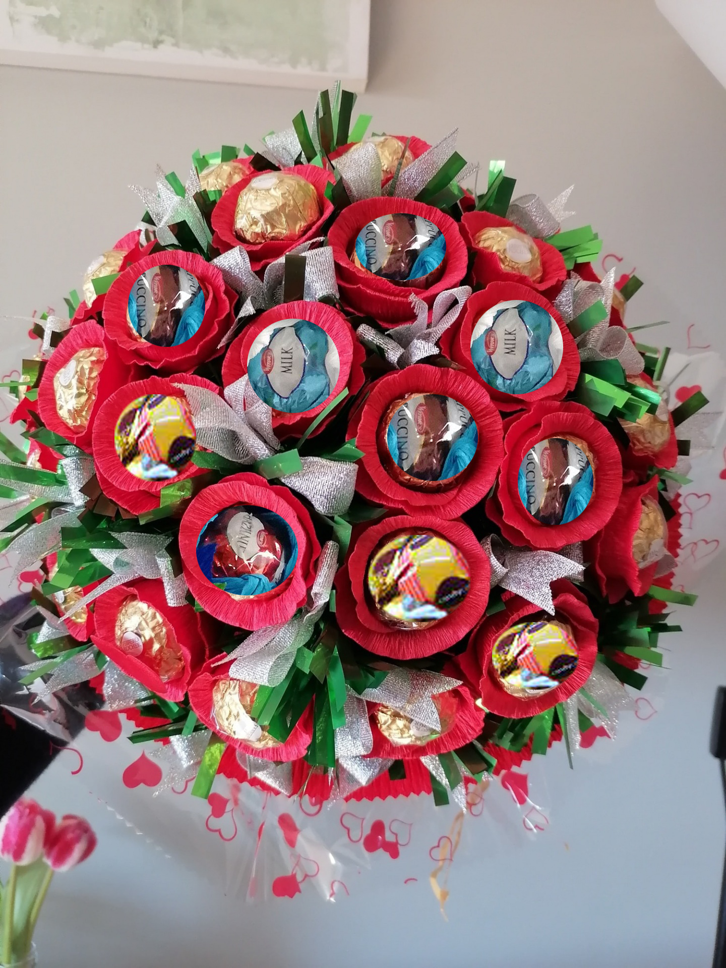 Bouquet de bombons Ferrero Rocher em papel vermelho, prata e verde sobre uma jarra.