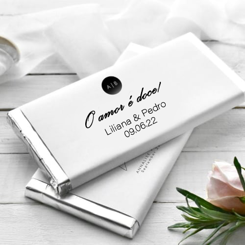 Barras de chocolate embrulhadas em papel branco com texto personalizado e flores ao lado
