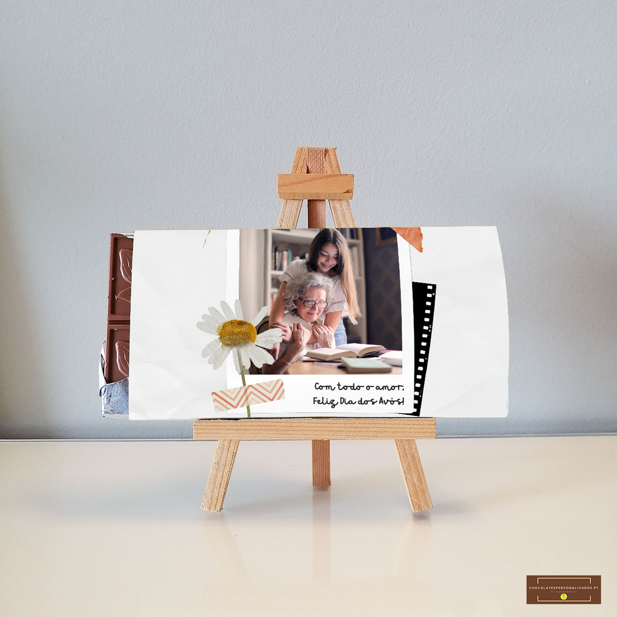 Barra de chocolate embrulhada com fotografia, texto e flor, em cavalete de madeira.