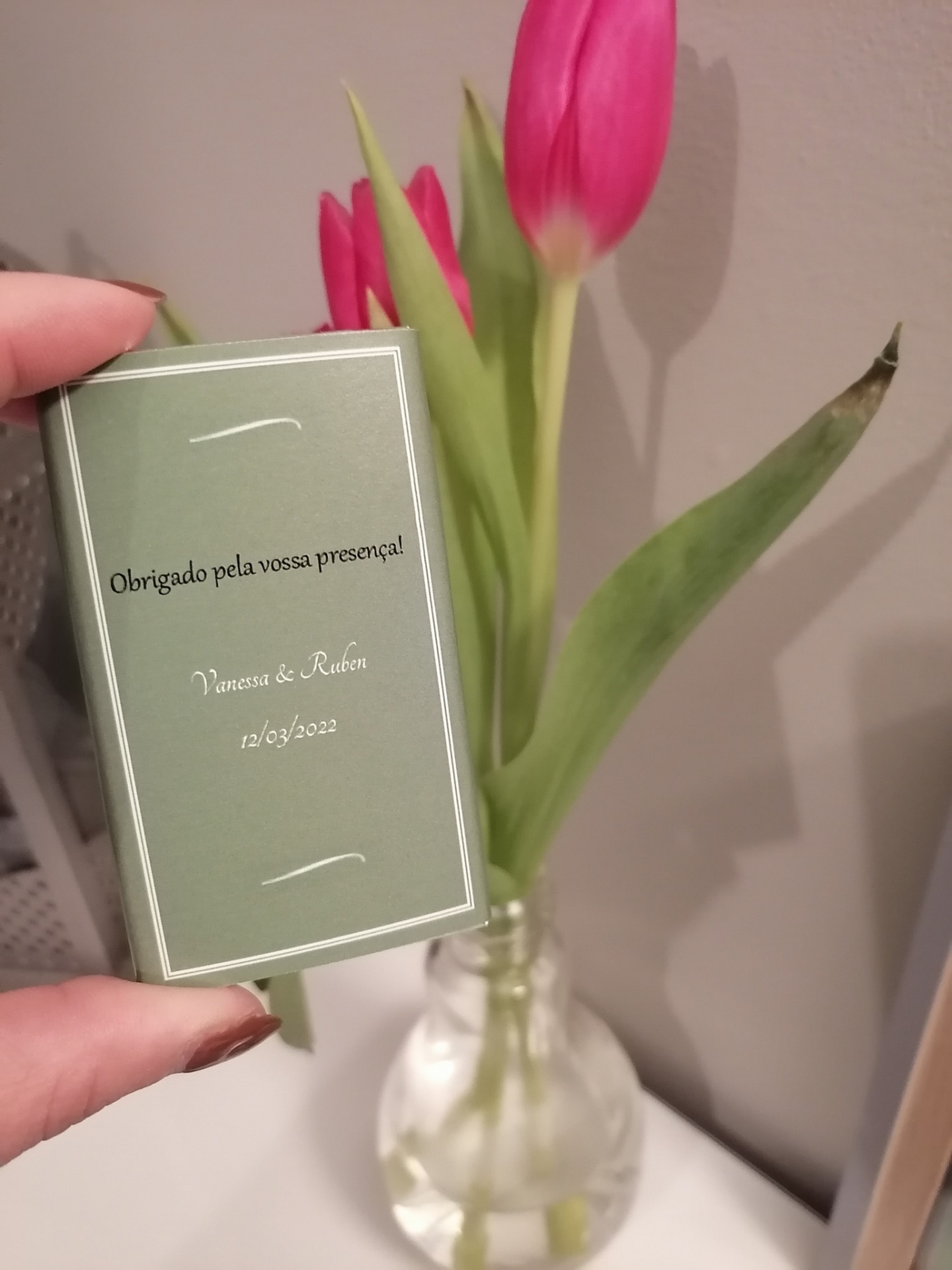 Embalagem verde com texto de agradecimento e vaso de vidro com tulipas rosas e folhas verdes