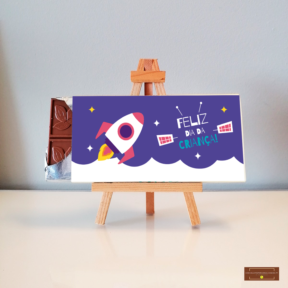 Barra de chocolate com embalagem ilustrada e texto 'FELIZ DIA DA CRIANÇA!'