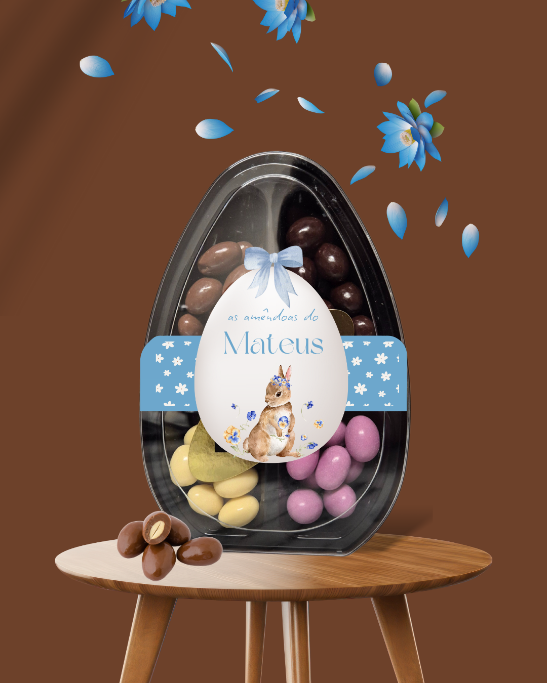 Ovo de embalagem com amêndoas coloridas de chocolate, etiqueta com coelho e texto, em mesa de madeira e fundo castanho com flores azuis