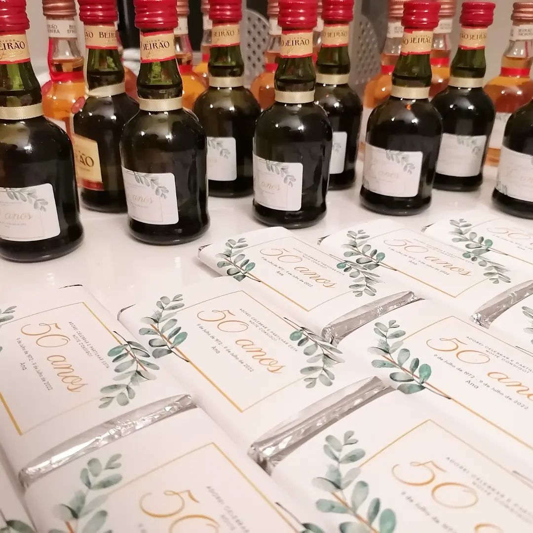 Garrafas pequenas e embalagens comemorativas de 50 anos sobre mesa branca