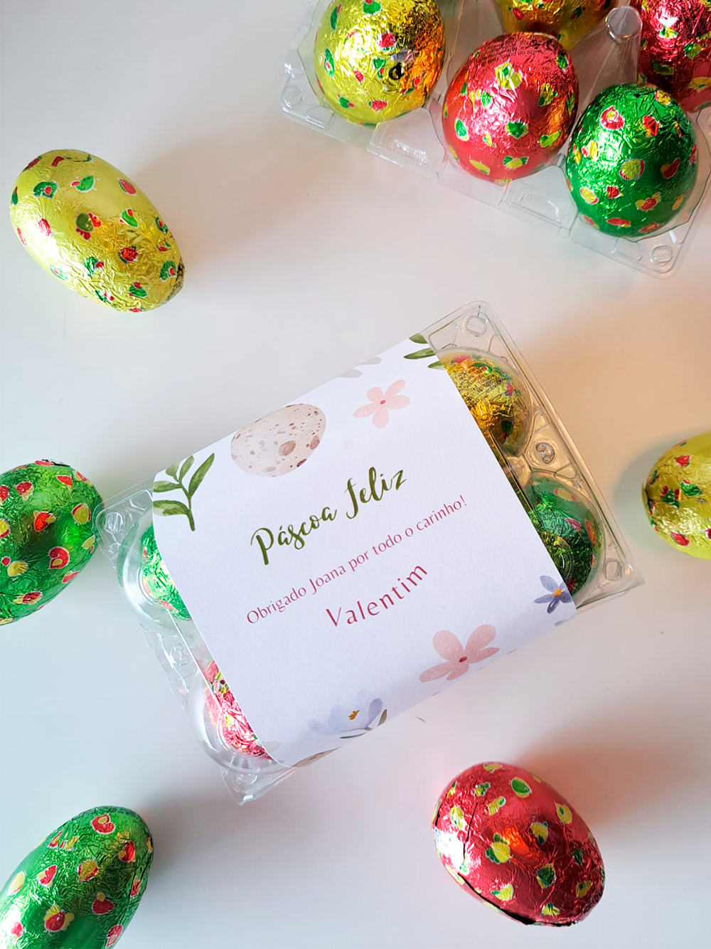 Ovos de chocolate coloridos em caixas plásticas com etiqueta branca de Páscoa