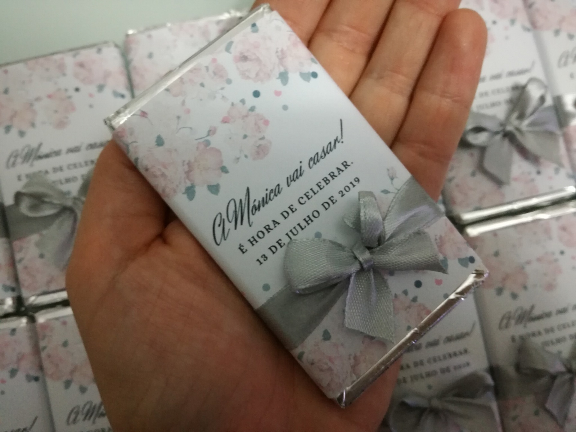 Chocolate embrulhado em papel floral com texto sobre casamento e laço cinzento