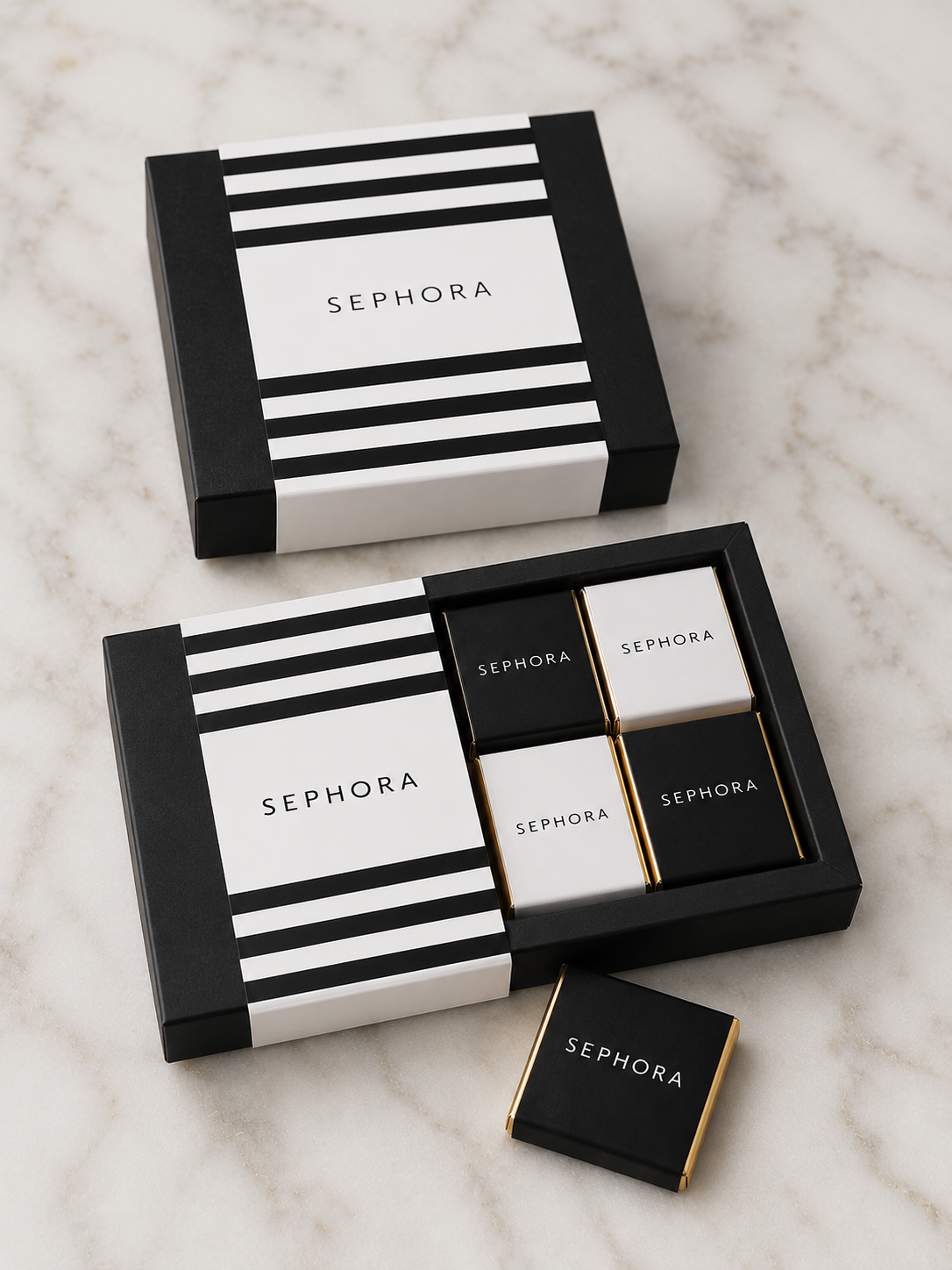 Caixa de presente Sephora com quatro pequenos embrulhos preto e branco sobre superfície de mármore.