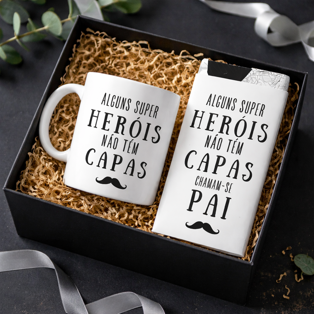 Conjunto de caneca branca e barra de chocolate com texto em preto dentro de caixa preta com enchimento de palha