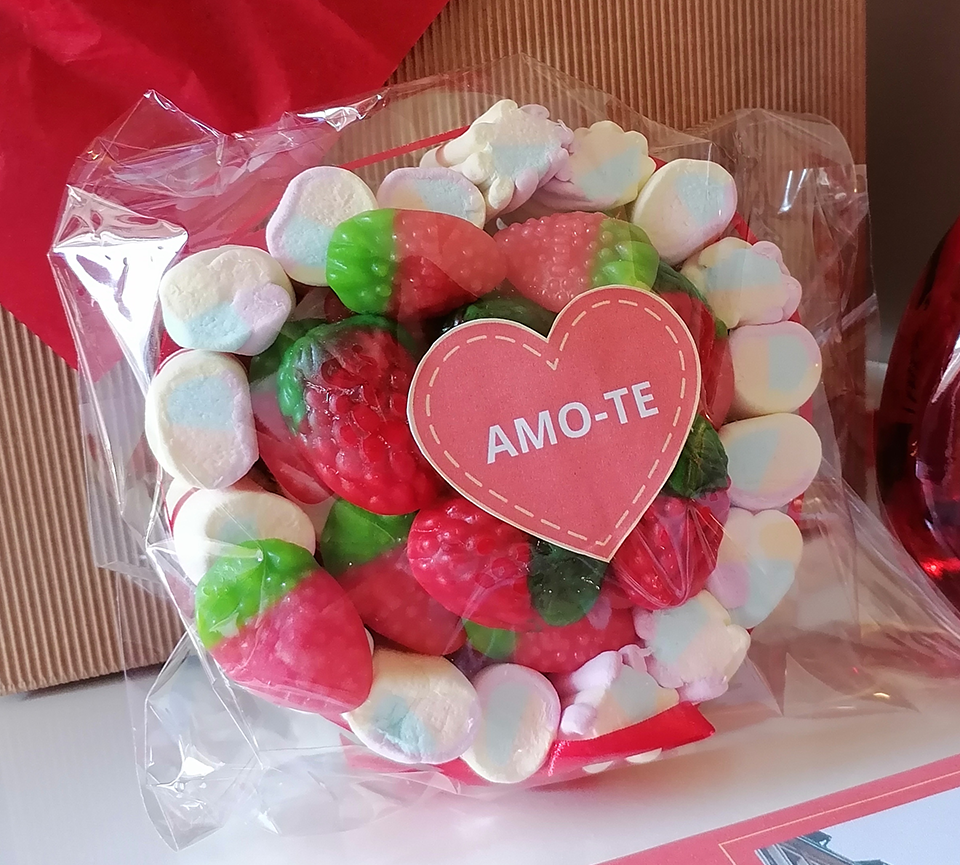 Doce em forma de morangos vermelhos e verdes com coração vermelho com texto 'AMO-TE', envolto em marshmallows e plástico transparente