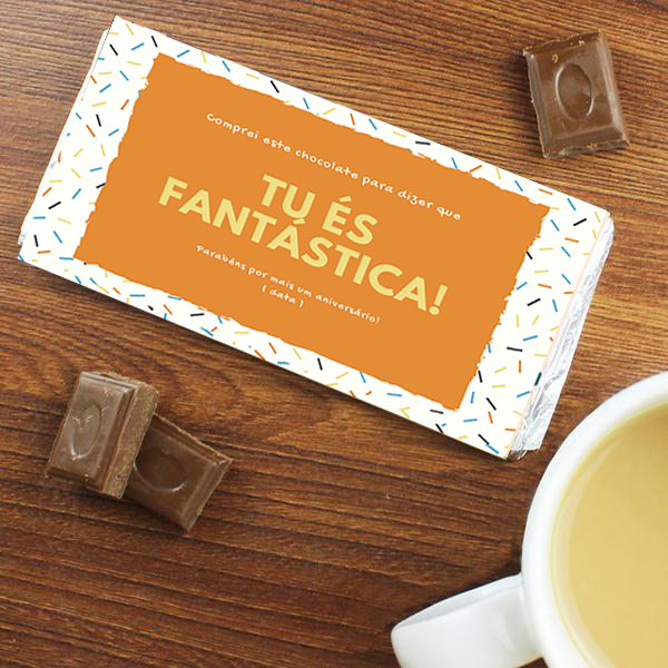 Barra de chocolate com embalagem branca e rótulo laranja com texto, pedaços de chocolate e chávena branca com bebida