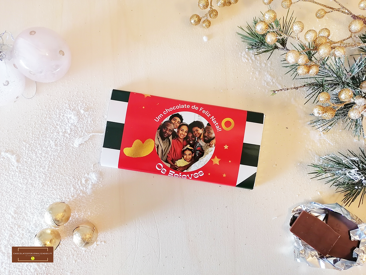 Caixa de chocolate com etiqueta vermelha e fotografia, decoração natalícia dourada e chocolate partido