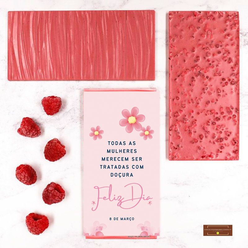 Tabletes de chocolate rosa com framboesas e embalagem com texto em português sobre fundo branco marmoreado.