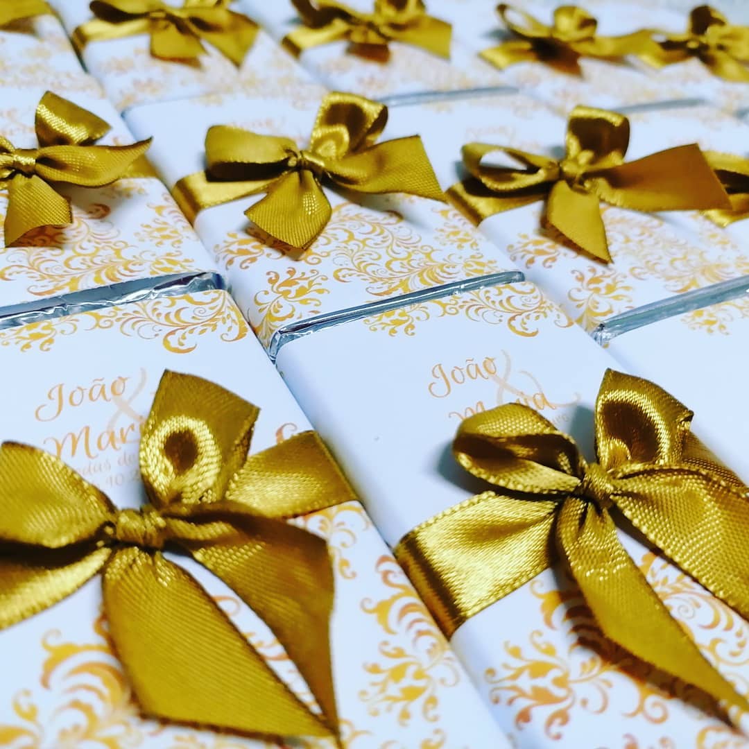 Embrulhos de chocolate branco com laços dourados e padrões decorativos